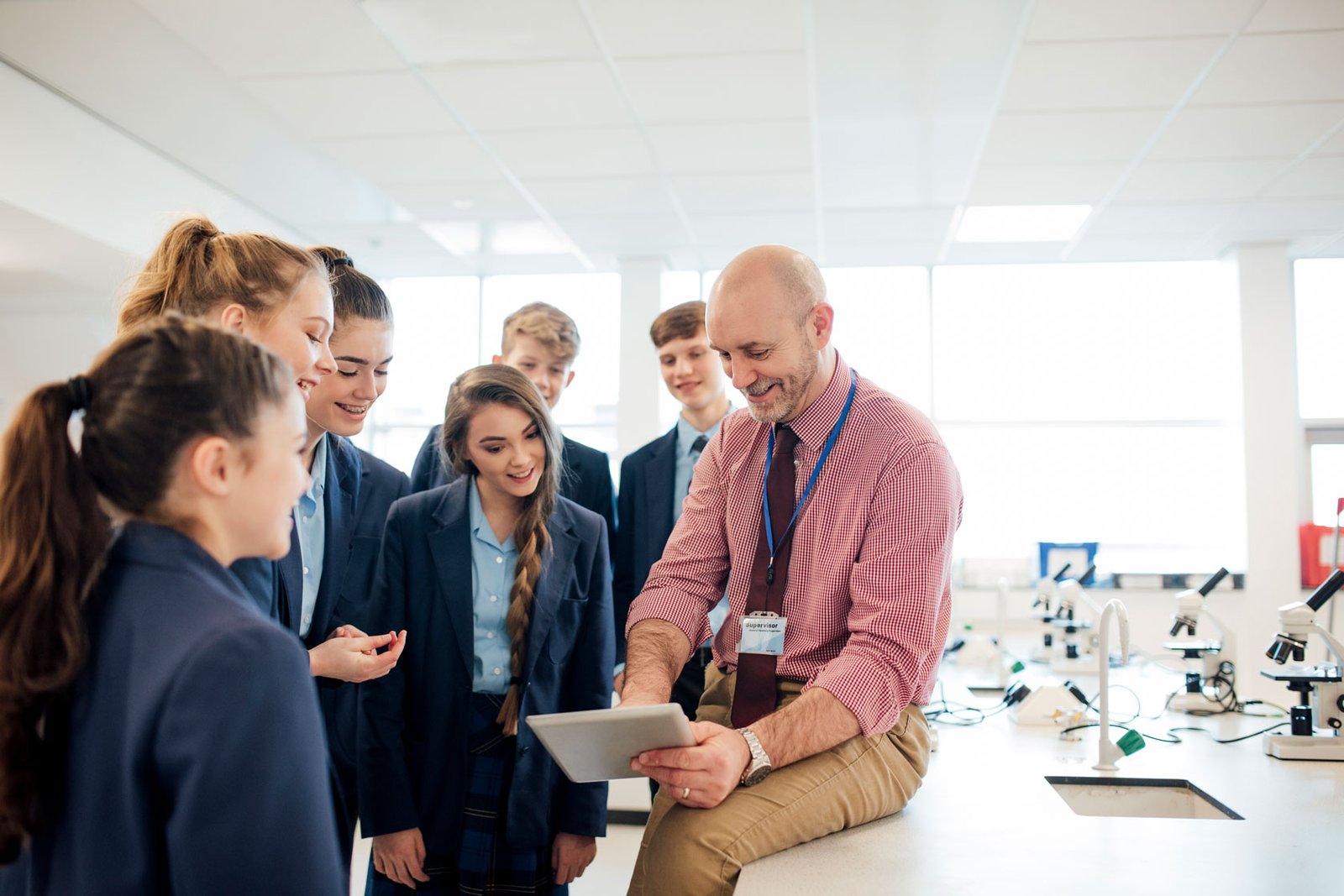 A male teacher talking to a group of students in a science room