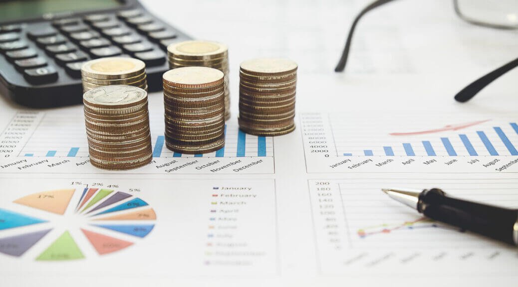 coins, calculator, glasses and graphs on table
