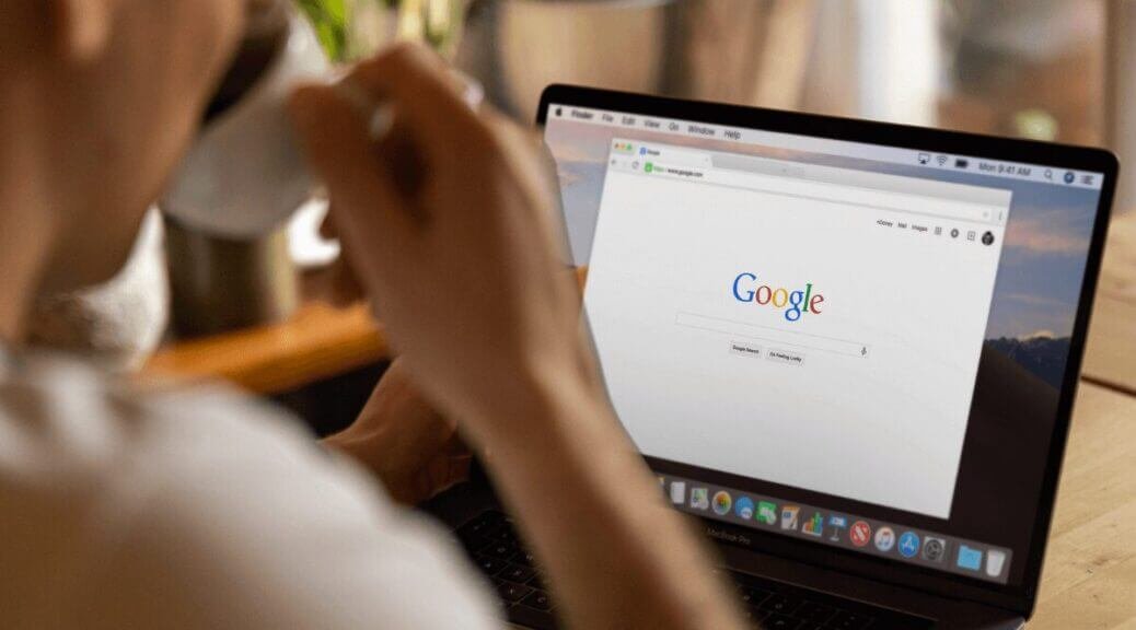 man drinking coffee, laptop in front of him with google on the screen