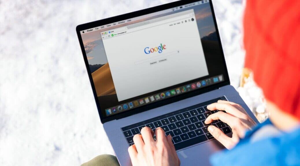 man typing on laptop, google homepage on screen